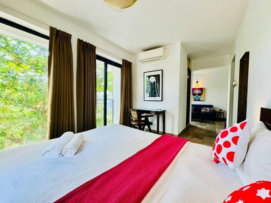 Une chambre d’hôtel avec un lit, un bureau et une vue sur la verdure.
