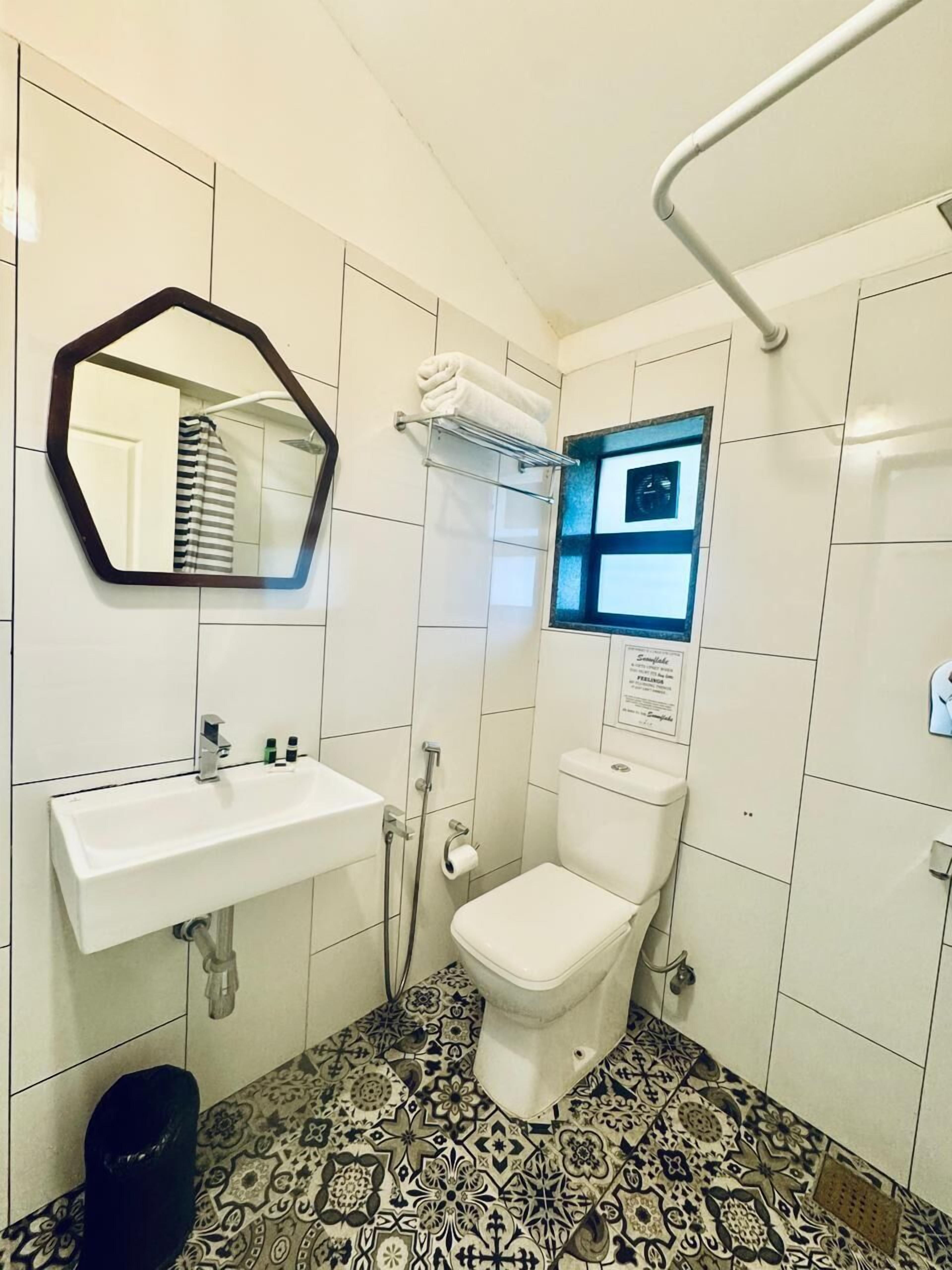 Un baño con lavamanos blanco, inodoro, espejo y ducha.