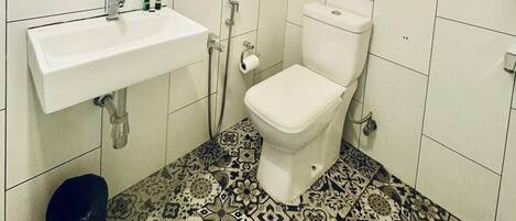 A bathroom with a white sink, a toilet, a mirror, and a shower.