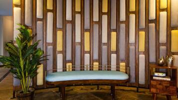 A room with a wooden bench, a potted plant, and a decorative wall with vertical panels.