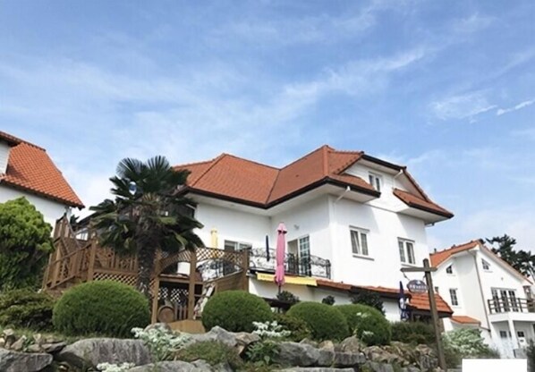 A two-story building with a red-tiled roof, white walls, and a balcony.