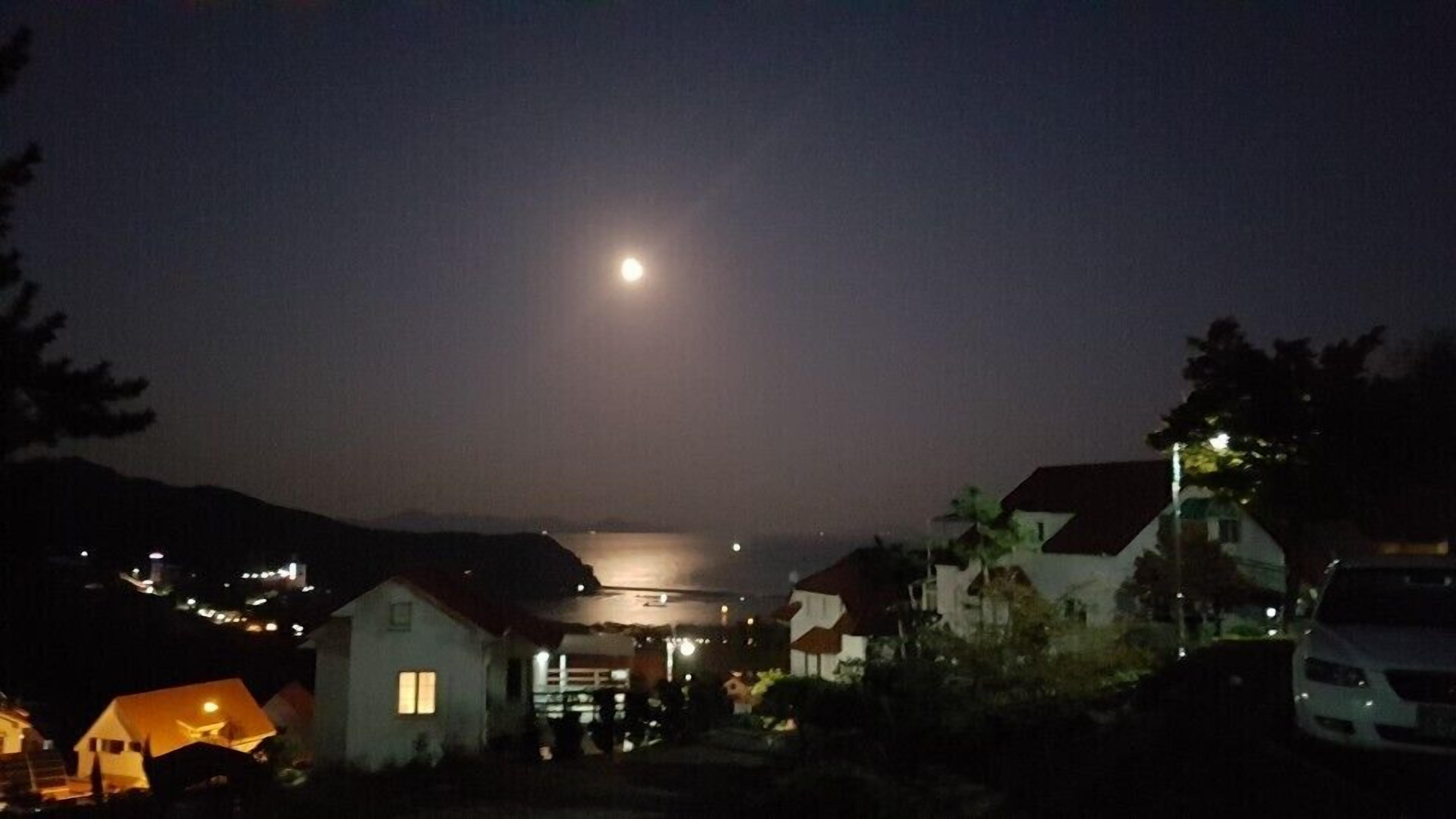 En nattbild av ett bostadsområde med hus och en synlig måne.