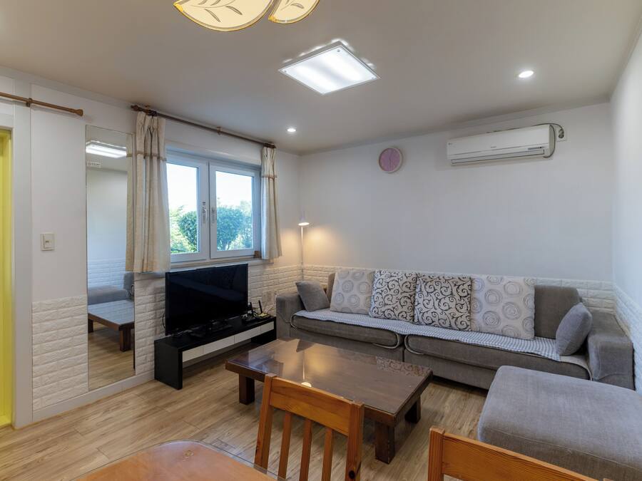 Una sala de estar con sofá, televisor, mesa y espejo.