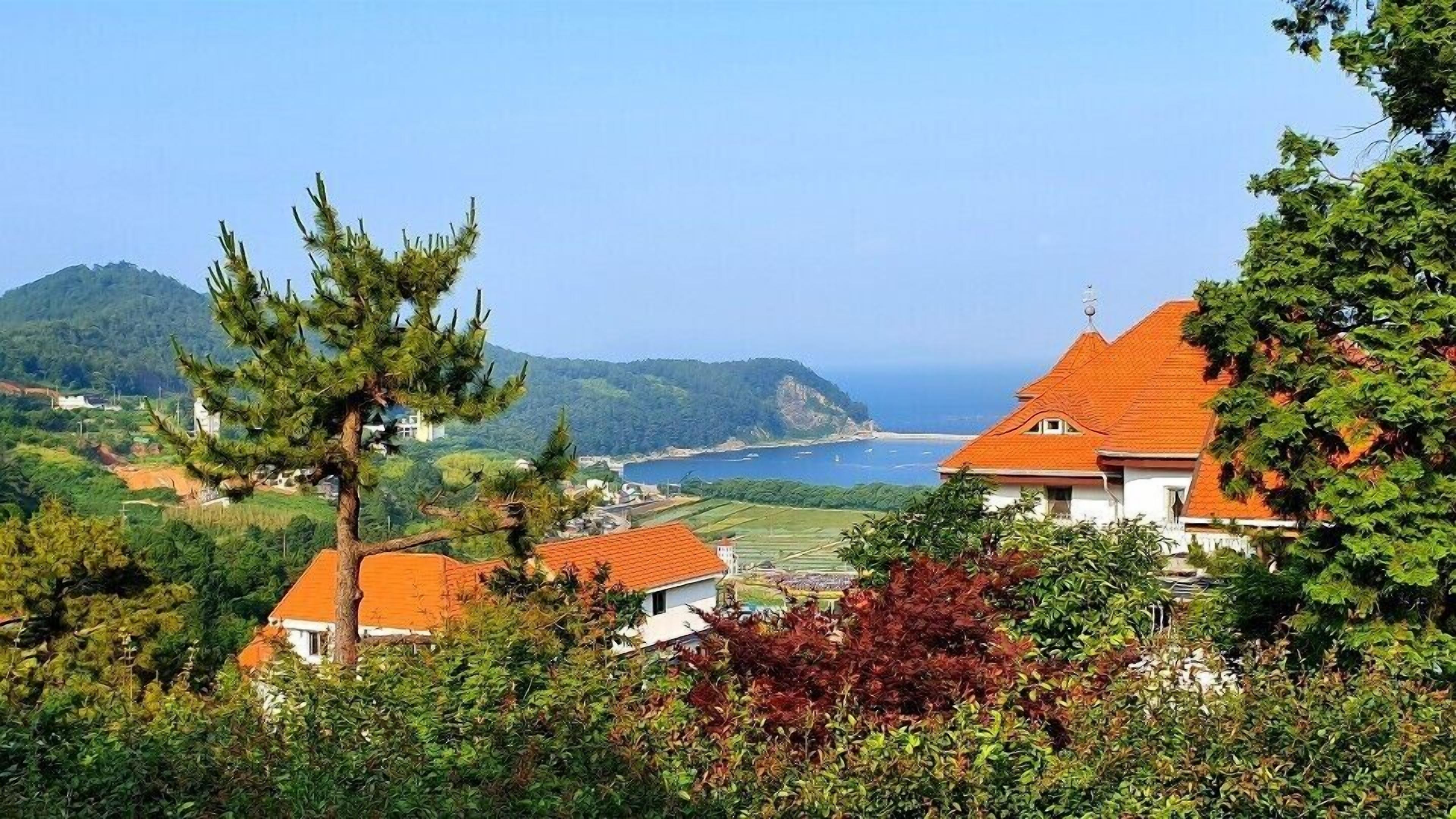 Blick auf die Küste mit Häusern, wolkenlosem Himmel und weiter See.