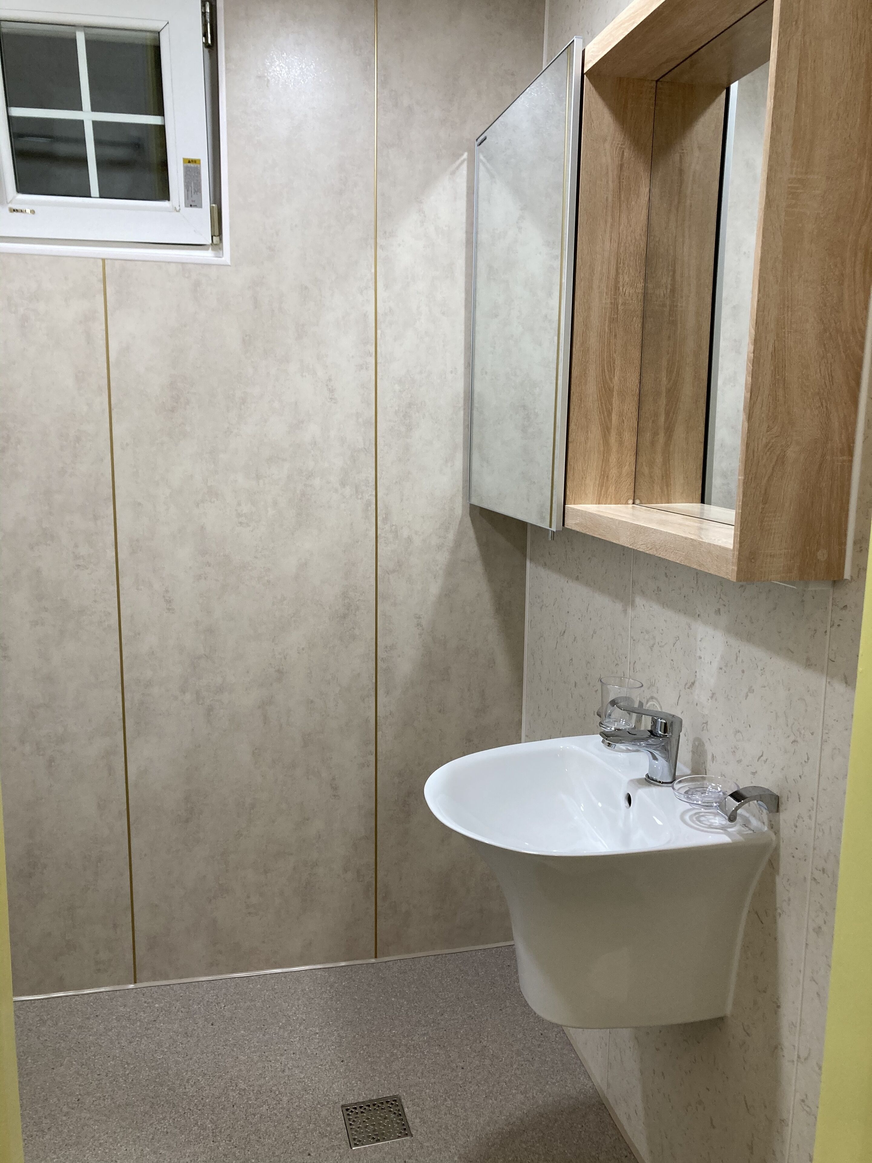 Une salle de bain avec un lavabo blanc, un miroir et une fenêtre.