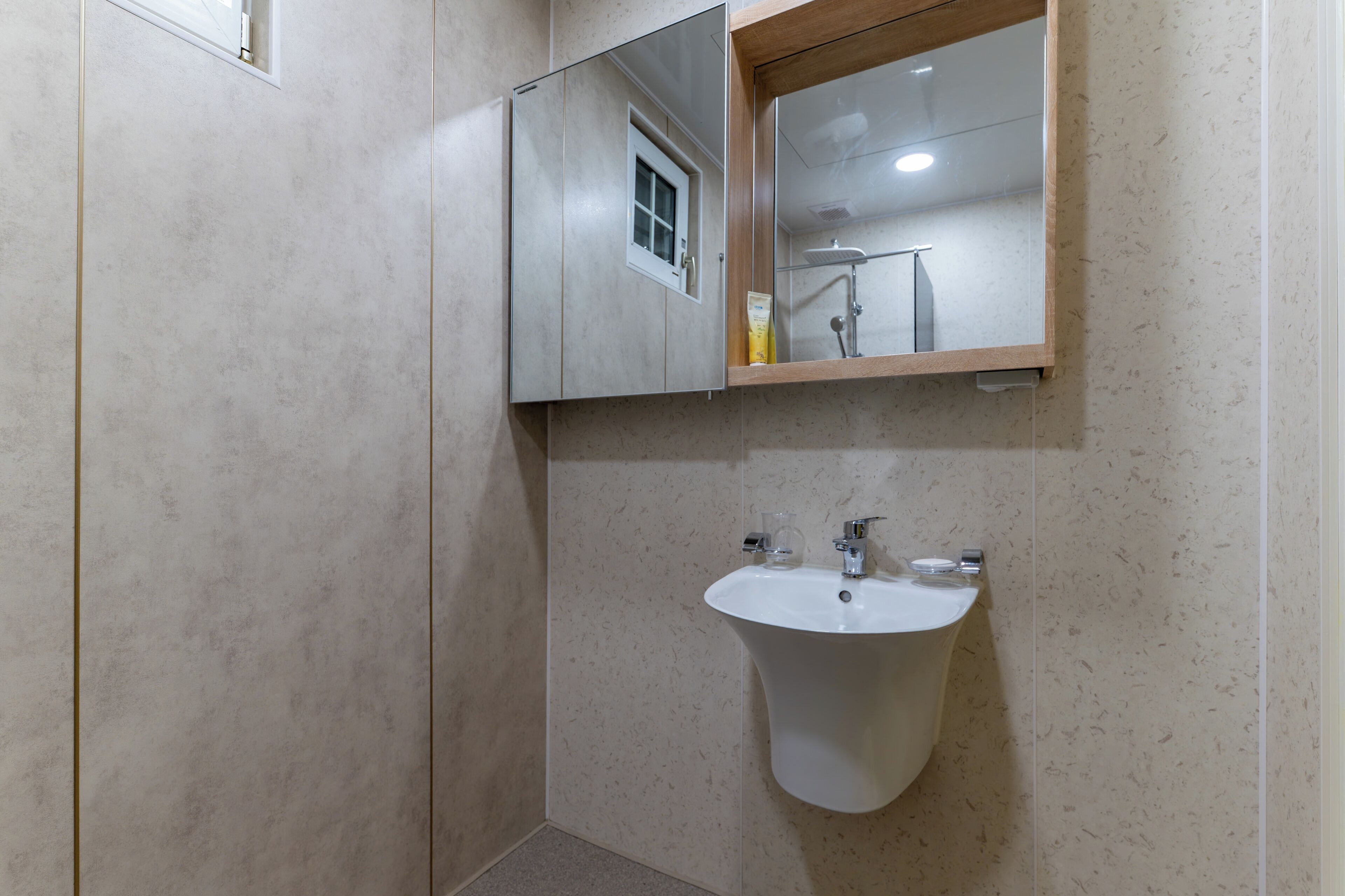 Een badkamer met een wit wastafelmeubel, een spiegel en een raam.