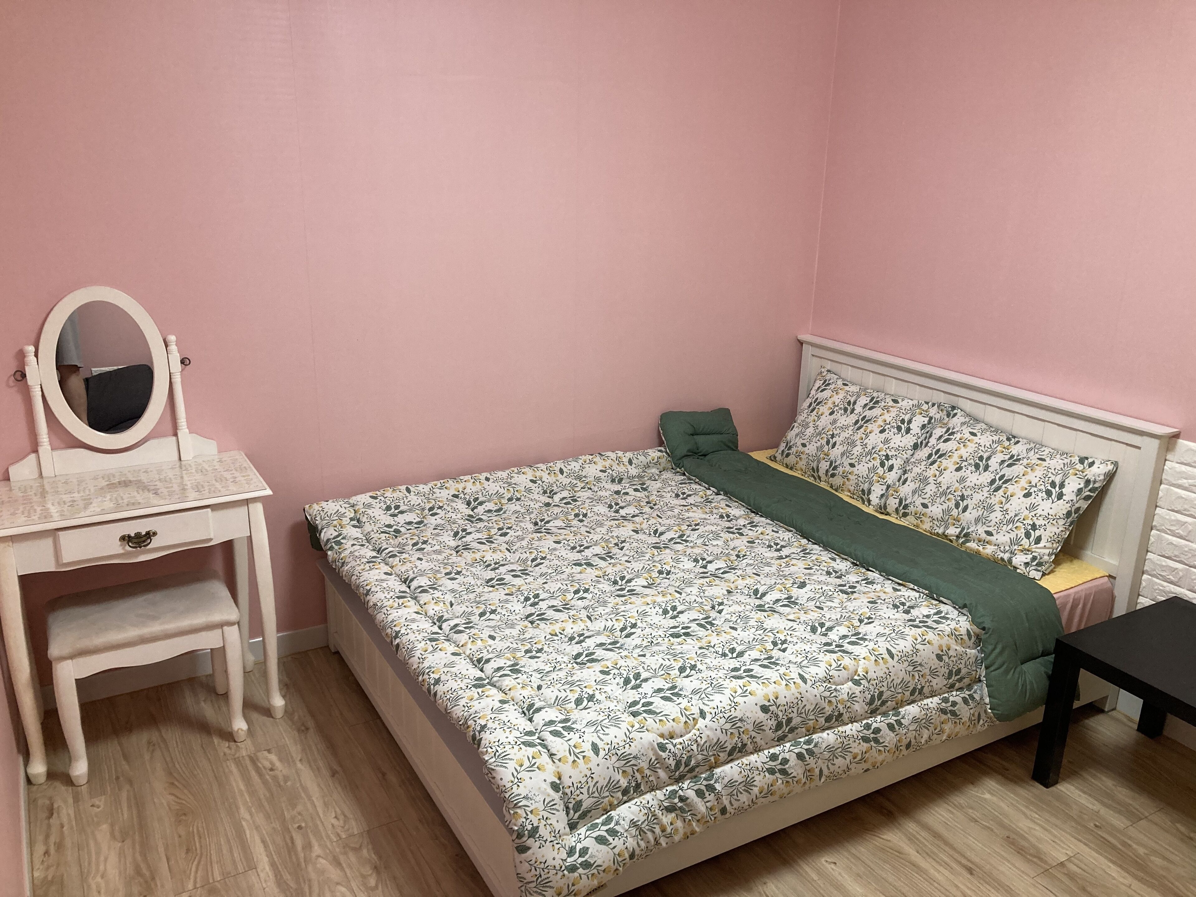 Una camera da letto con un letto, un comodino, una cassettiera e uno specchio.