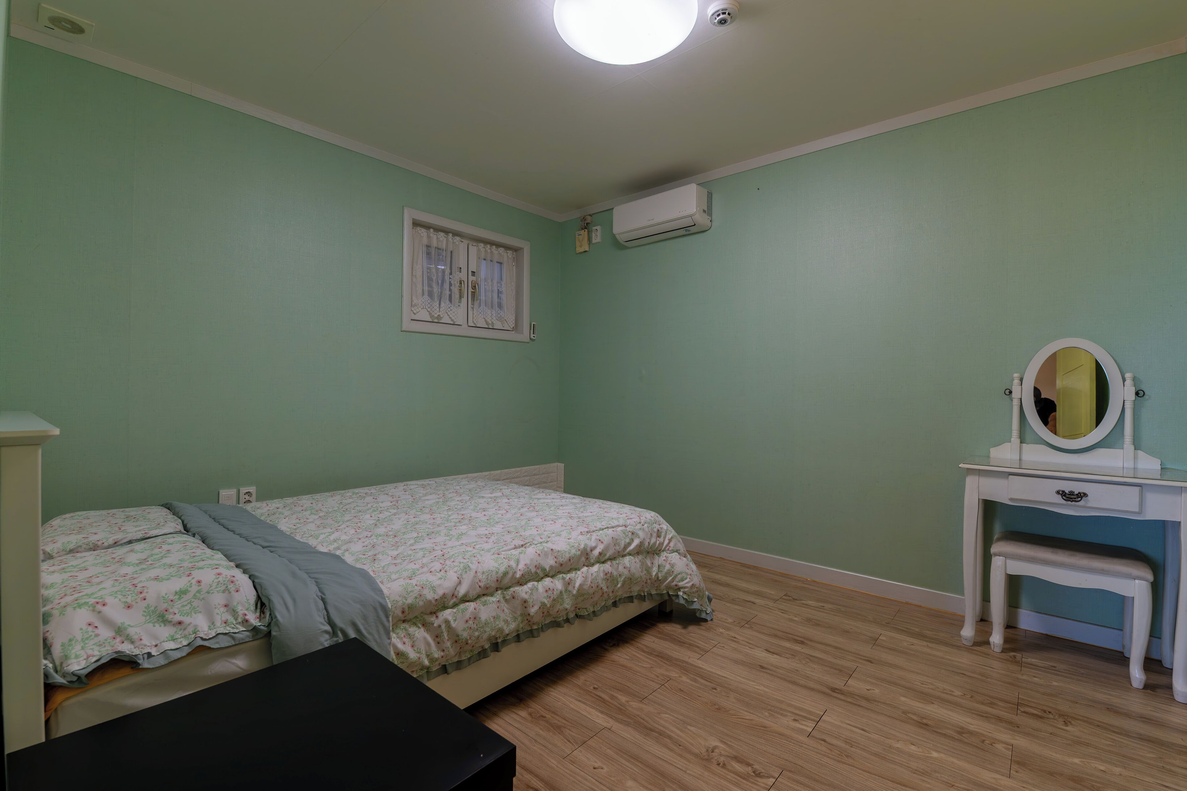 Una camera da letto con un letto, una toeletta con specchio e un condizionatore d'aria a parete.