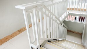 A white staircase with a wooden handrail and a tiled floor.