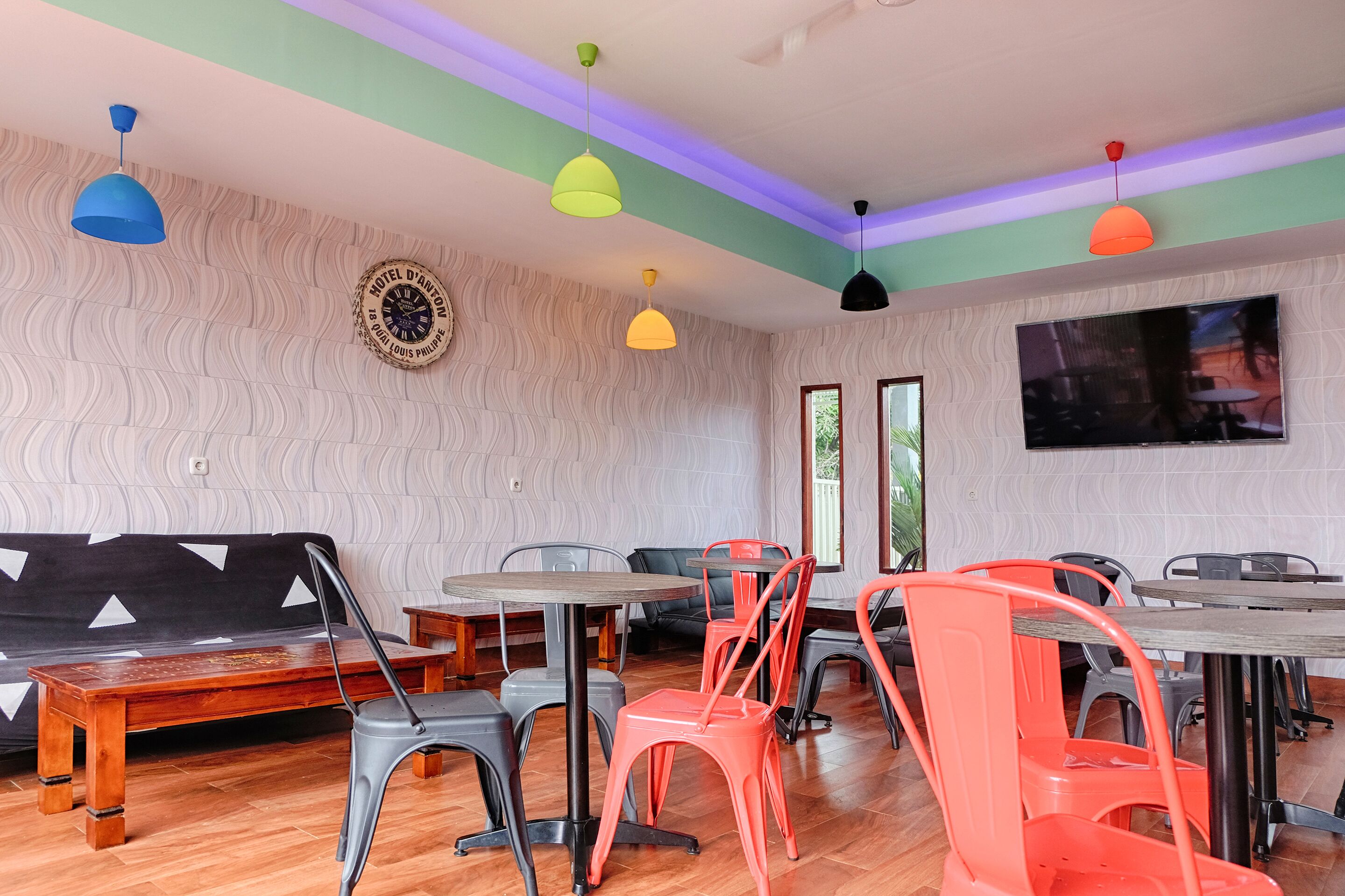 Un comedor con varias mesas y sillas, un sofá y un televisor en la pared.