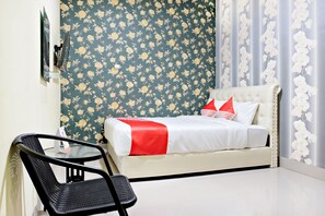Una habitación de hotel con cama, una silla y un espejo.
