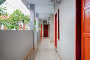 A corridor with a red door, a sign indicating a room for the hearing impaired, and a red wall.