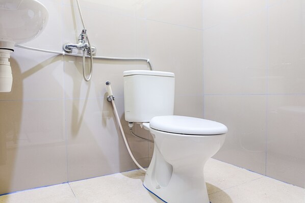 A modern bathroom with a toilet, a shower, and a visible pipe.