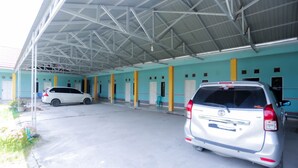 A covered parking area with two cars parked under a metal roof. - OYO 2692 Penginapan Mba Ros (Banjarbaru)