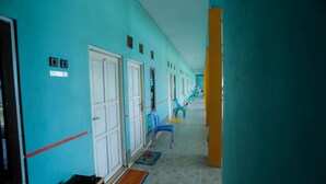 A long corridor with teal walls, white doors, and a bench. - OYO 2692 Penginapan Mba Ros (Banjarbaru)