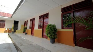 Un bâtiment doté d’une galerie couverte, de plantes en pot et d’une porte avec une fenêtre.