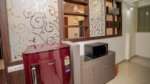 A compact kitchen with a refrigerator, microwave, and a decorative cabinet. - StayEden - Gracia Heights - 2 BHK (Indore)