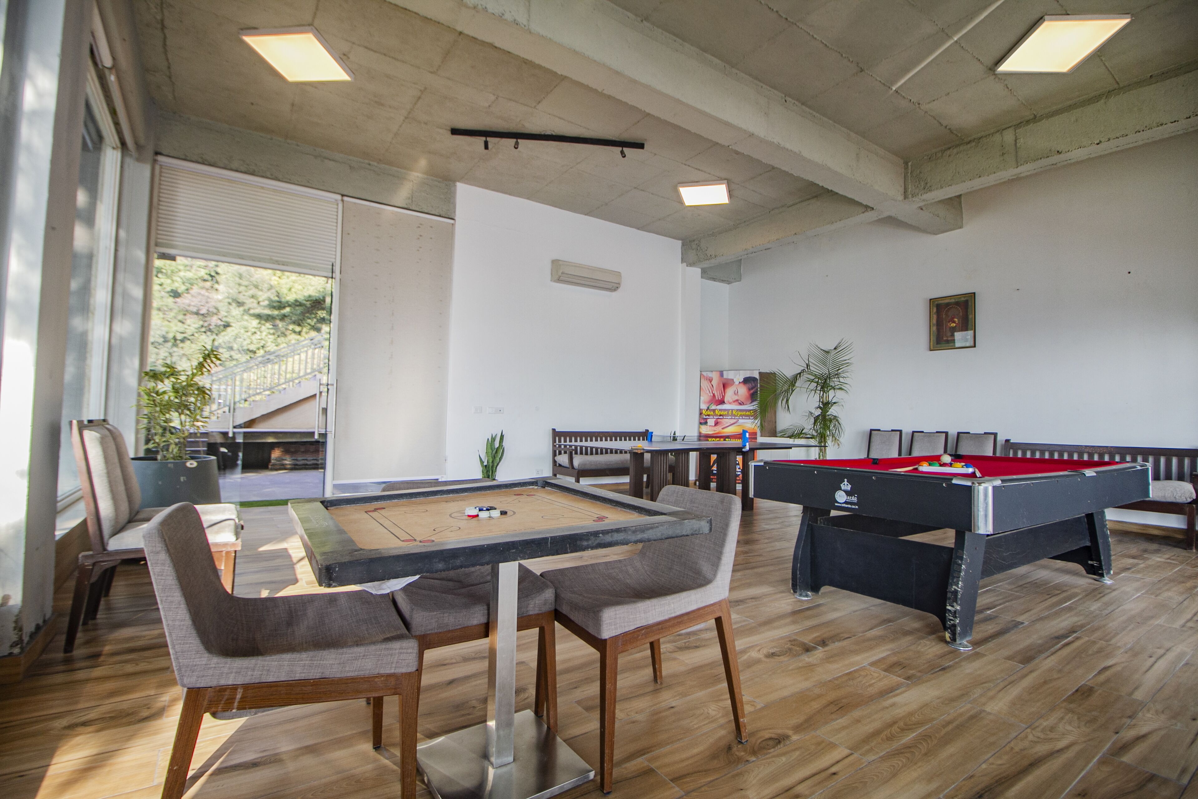 Ein Raum mit Billardtisch, Kicker und Poolbillard. Es gibt Stühle und ein Sofa.
