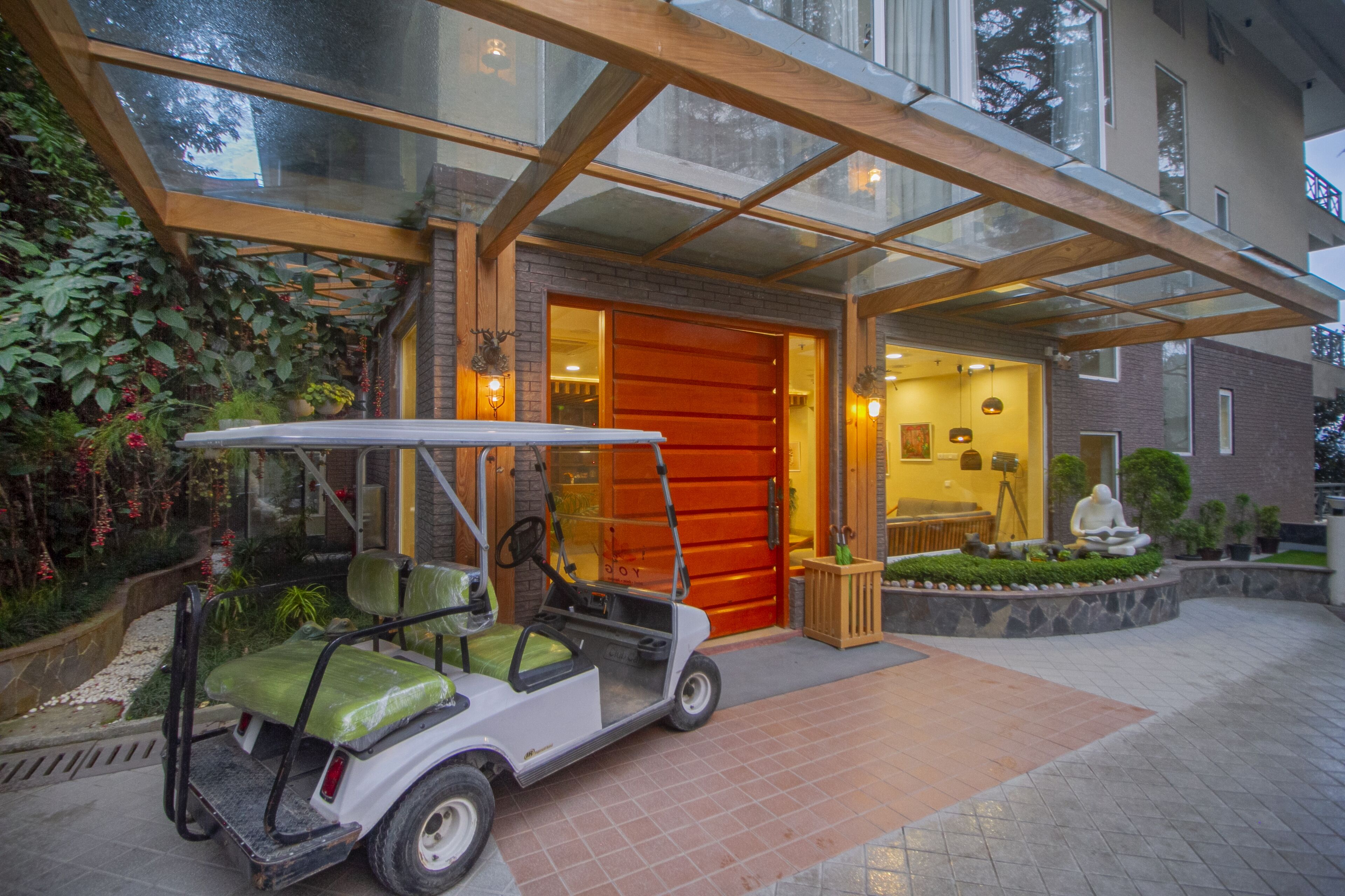 Une voiturette de golf est garée devant un bâtiment dont l’entrée est en verre et la porte est rouge.