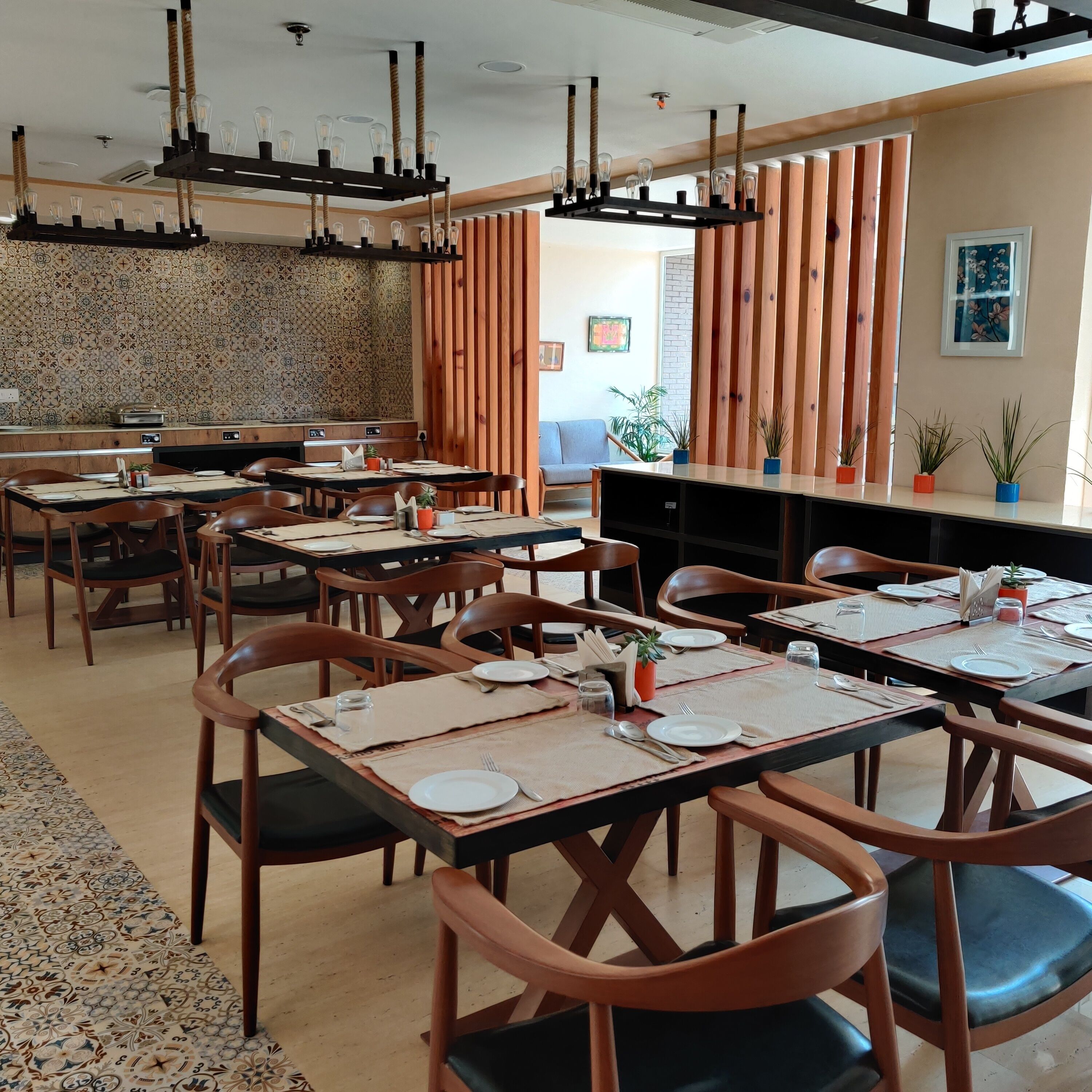 A restaurant with multiple tables and chairs, a patterned wall, and a wooden partition.