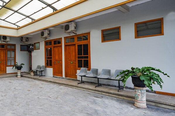 A waiting area with a long bench, potted plants, and a glass ceiling. - OYO 2737 D'KostNearKraton mangkunegaran (Surakarta)