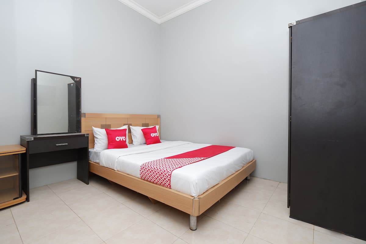 A bedroom with a bed, a desk, a wardrobe, and a mirror.