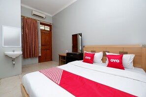 A hotel room with a bed, a wooden headboard, a mirror, a sink, and a wardrobe. - OYO 2737 D'KostNearKraton mangkunegaran (Surakarta)