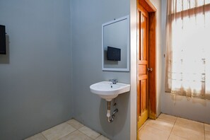 A bathroom with a white sink, a mirror, and a wooden door. - OYO 2737 D'KostNearKraton mangkunegaran (Surakarta)