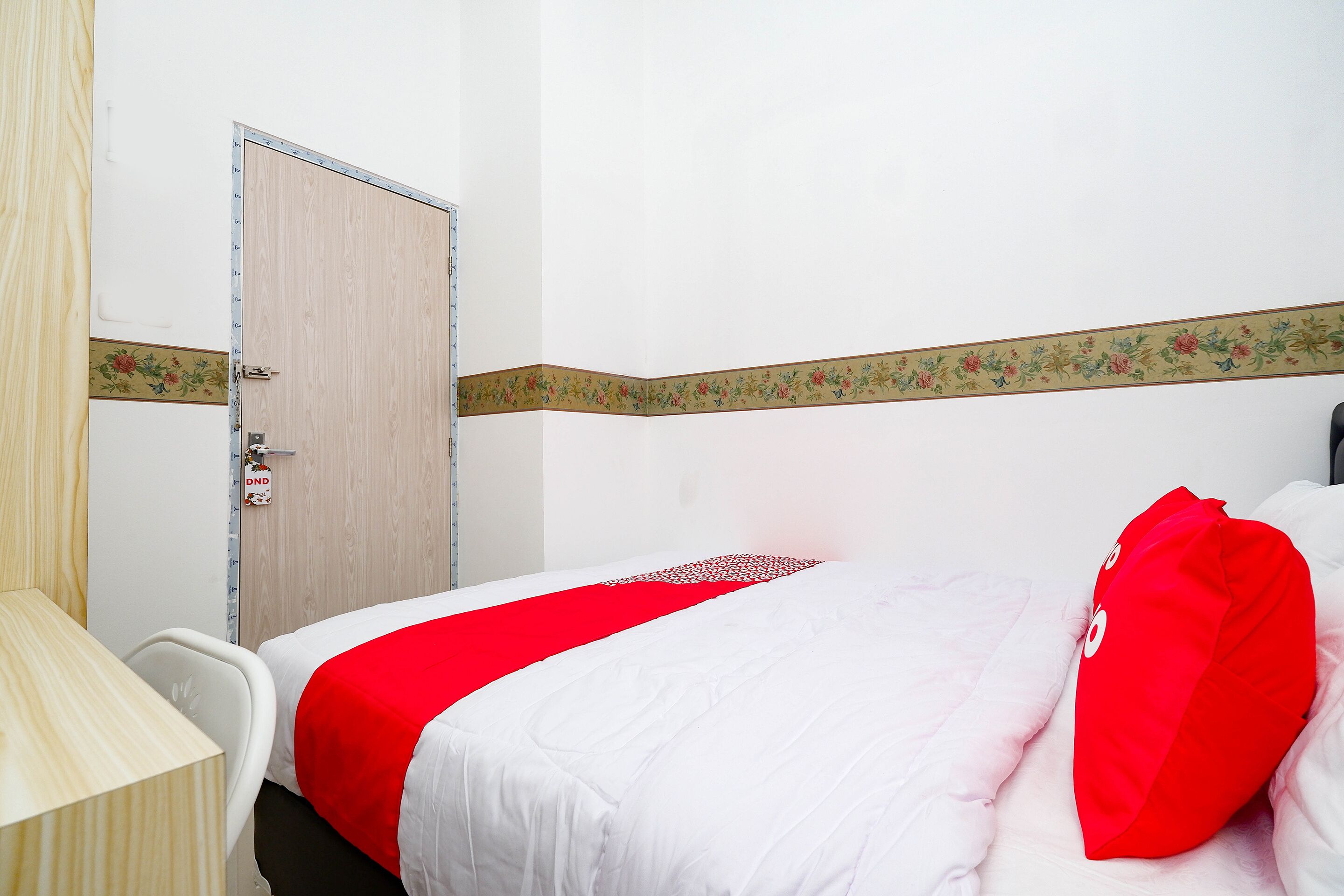 A hotel room with a bed, a desk, and a door.