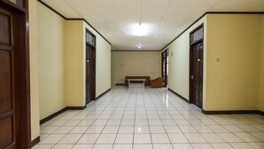A hallway with tiled flooring, wooden doors, and a bench in the center. - Super OYO 2672 Bee M Syariah (Bandung)