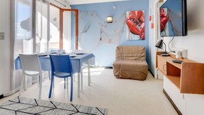 Un salon moderne comprenant un coin repas, une grande fenêtre et un téléviseur à écran plat fixé au mur.