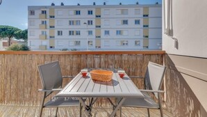 Un balcon avec une table et des chaises, un panier en osier et deux tasses.