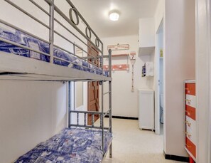 Une chambre avec un lit superposé, un petit bureau et un réfrigérateur.