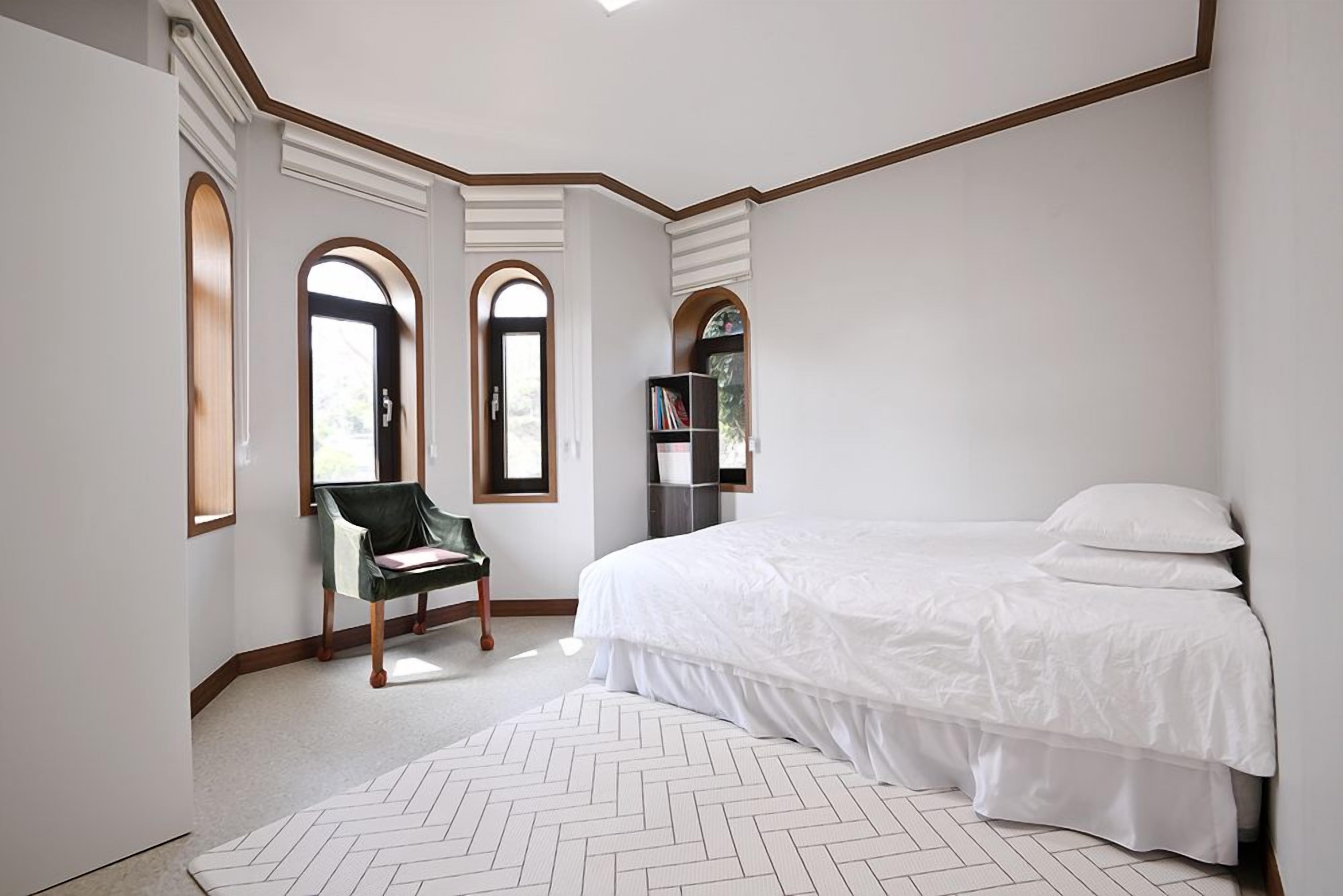 Une chambre avec un grand lit, une chaise et une bibliothèque.