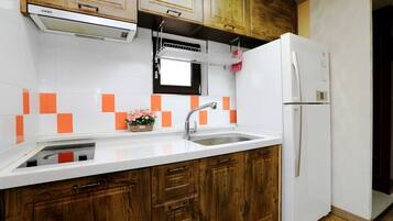 A kitchen with wooden cabinets, a white countertop, a sink, a built-in oven, and a refrigerator.