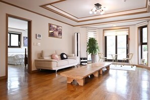 Un salon spacieux avec une table basse en bois, un canapé et une grande fenêtre laissant entrer la lumière naturelle.