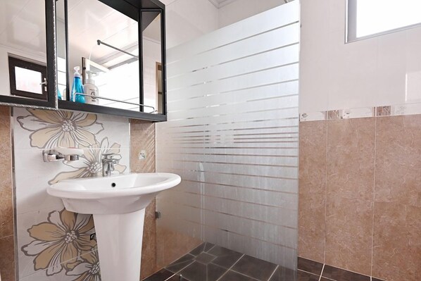 A bathroom with a white sink, a mirror, and a shower with frosted glass doors.