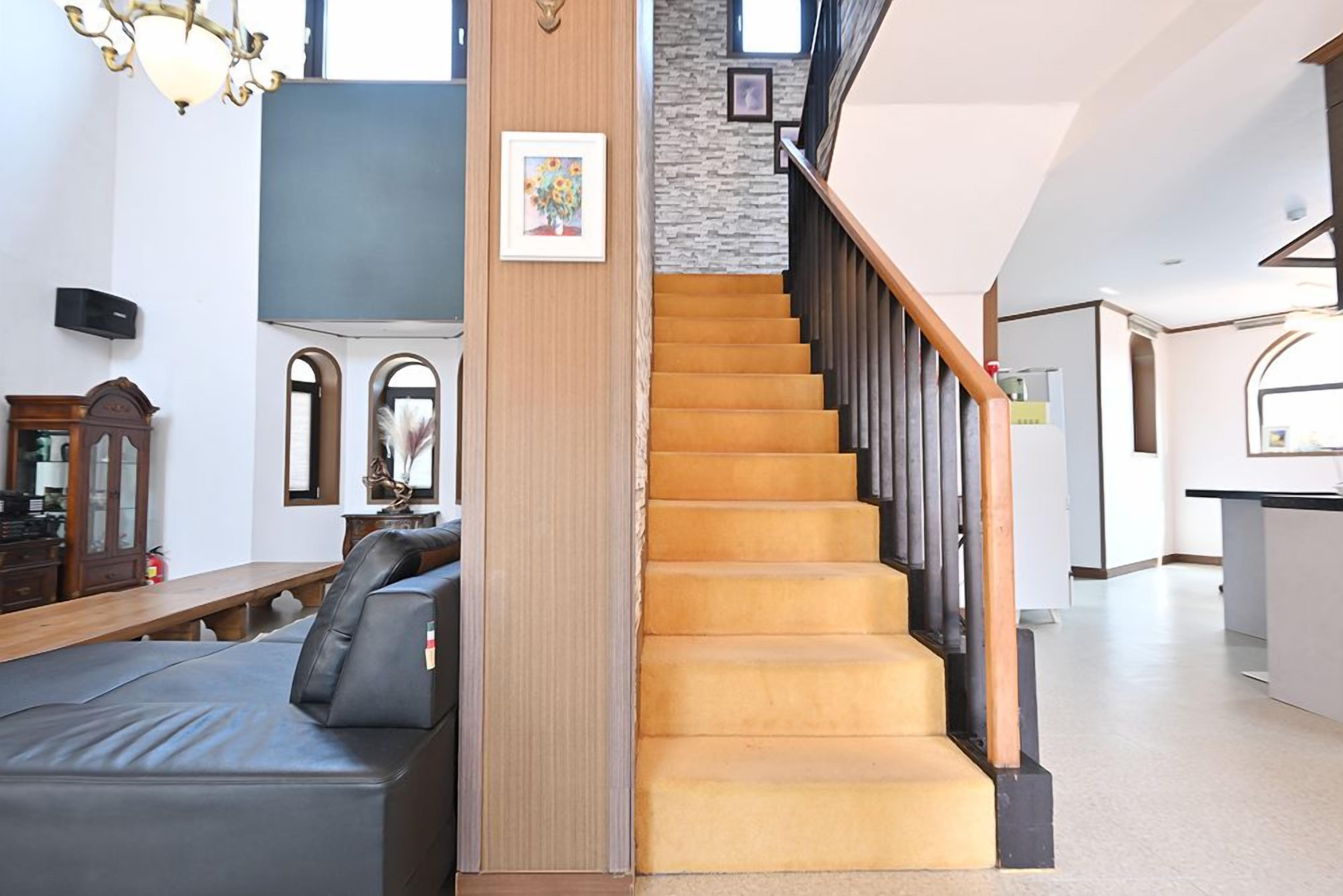 Un escalier avec des marches en bois et une rampe noire, menant à un deuxième étage.