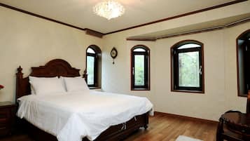 A bedroom with a large bed, wooden headboard, and three arched windows.