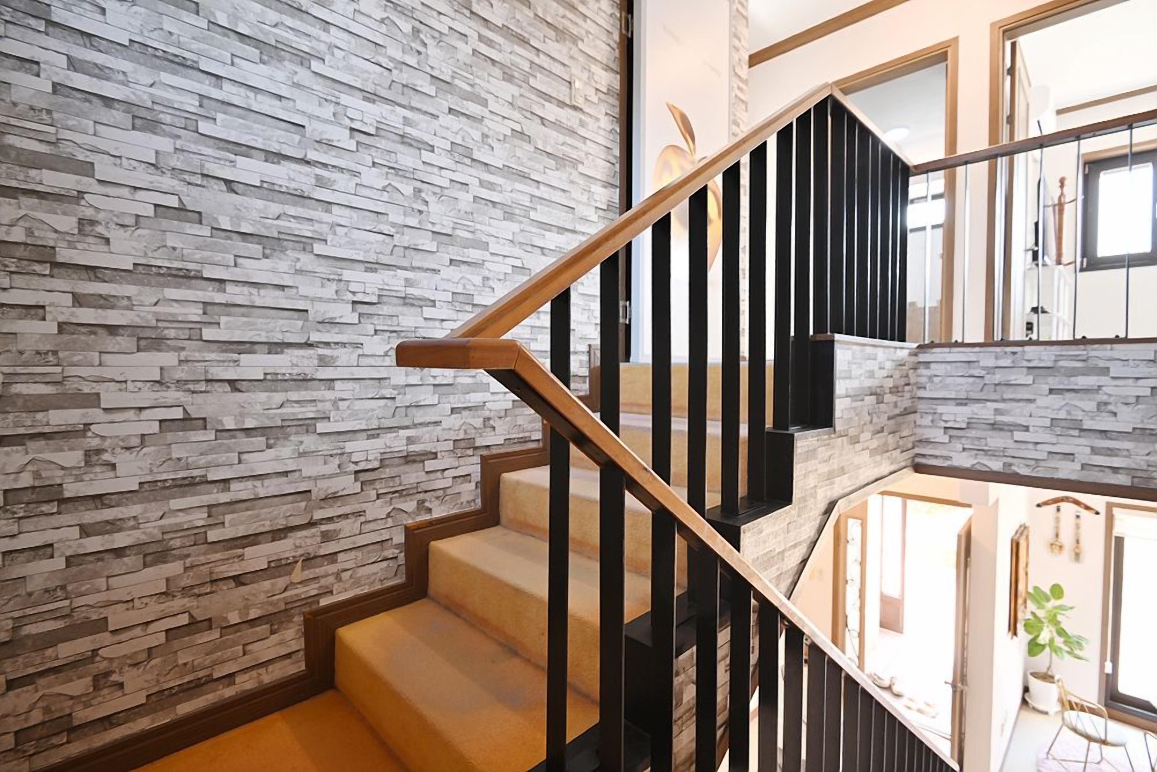 A staircase with a stone wall on one side and a wooden railing.