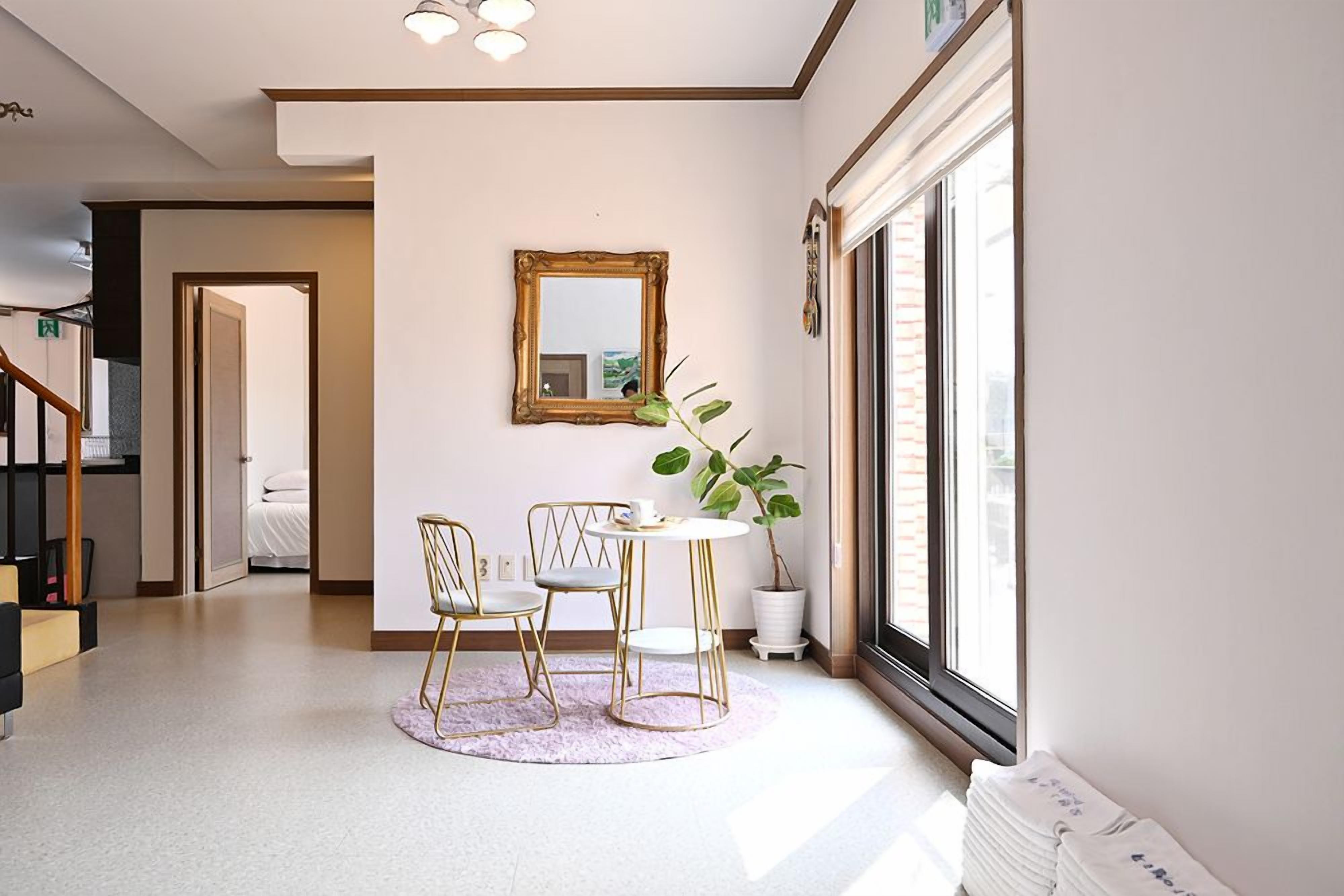 A modern interior with a dining area, a large mirror, and a potted plant.