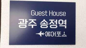 Un letrero con la inscripción 'Guest House' y texto en coreano, que indica un alojamiento para huéspedes.