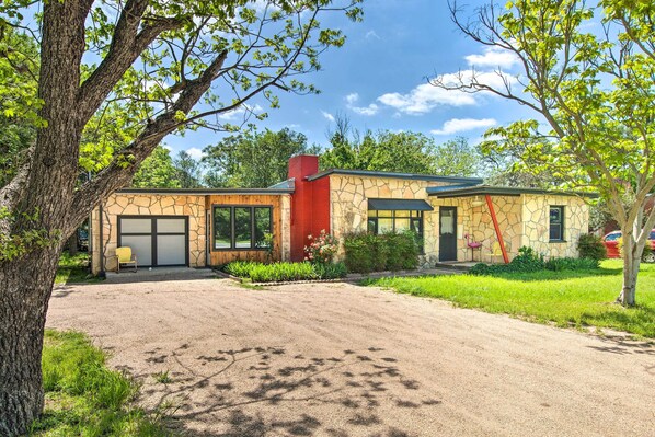 Une maison à deux étages avec une façade en pierre, une cheminée rouge et un garage.