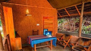 A rustic wooden room with a thatched roof, a table with chairs, and hanging lights. - Sea View Clay House Dikwella (Dikwella)
