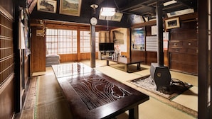 A traditional Japanese room with tatami flooring, a low table, and a wood stove. - Shirakawago Gassho-house YOKICHI (Shirakawa)