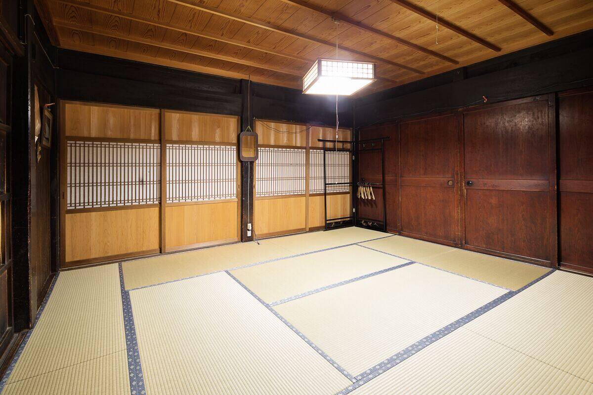 A traditional Japanese room with tatami flooring, sliding doors, and a hanging lantern.