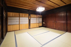 Una habitación japonesa tradicional con suelo de tatami, puertas correderas y un farol colgante.