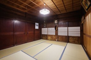 Una habitación japonesa tradicional con suelo de tatami, puertas correderas de madera y una lámpara colgante.