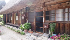 A traditional wooden building with a thatched roof, wooden doors, and a sign indicating it is a hotel. - Shirakawago Gassho-house YOKICHI (Shirakawa)