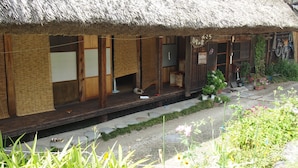A traditional thatched-roof building with wooden sliding doors and a small porch area. - Shirakawago Gassho-house YOKICHI (Shirakawa)